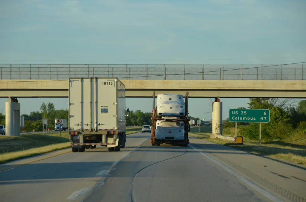 A couple of trucks driving down a highway under a bridge