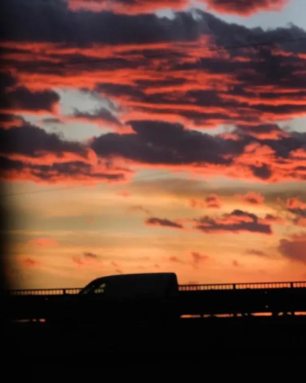 a truck driving down a road under a cloudy sky